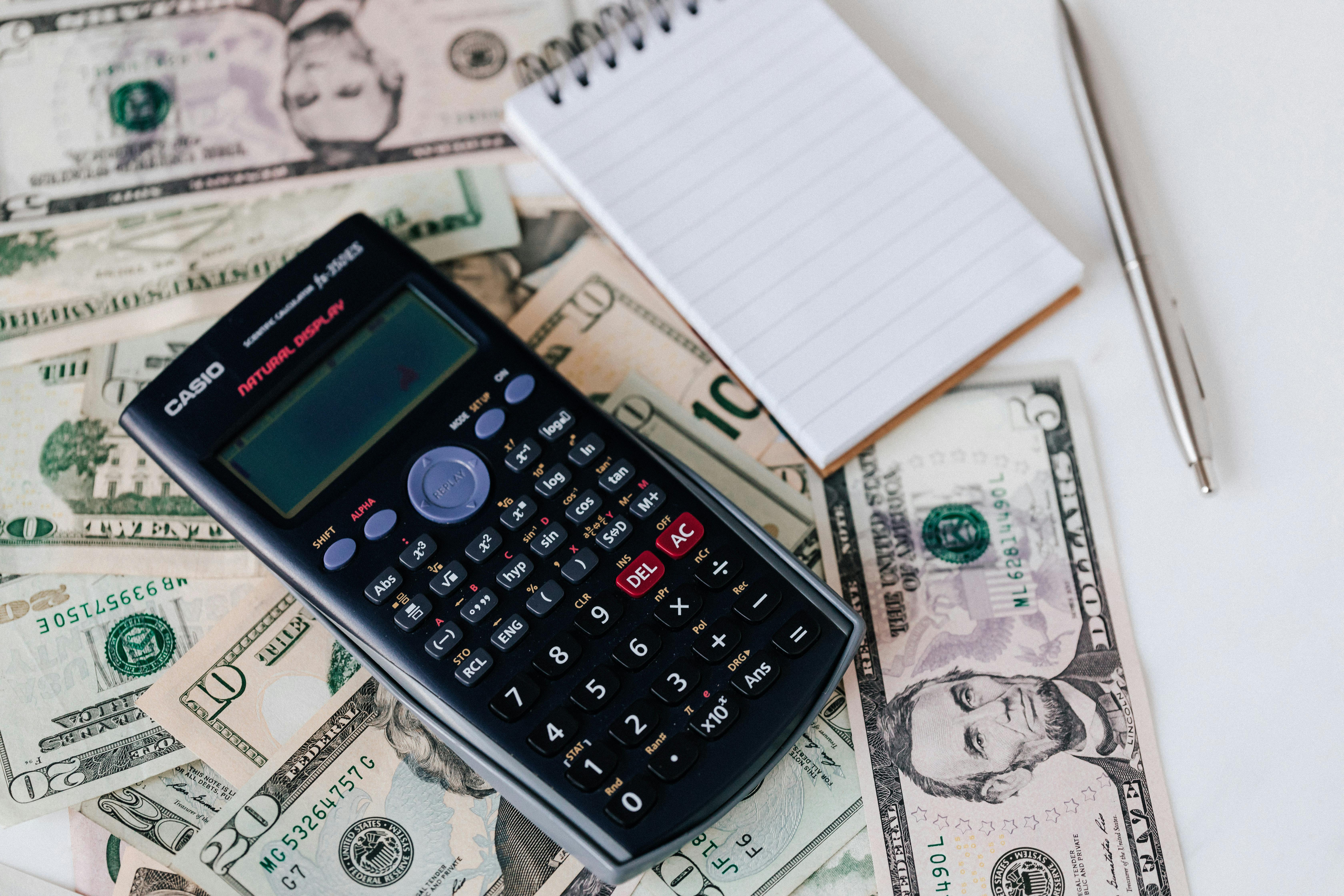 calculator and cash next to notepad